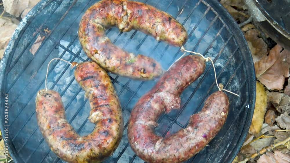 Grilling sausages on barbecue grill. BBQ with fiery sausages on the grill. Grilling sausages on barbecue grill. BBQ with fiery sausages on the grill.