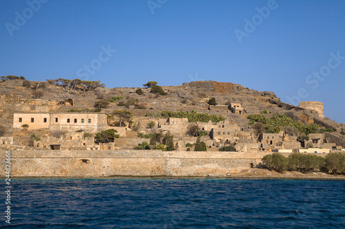 Cruise to the island of Spinalonga. Small boat on the blue lagoon. Spinalonga fortress on the island of Crete, Greece. Architecture on the island.
