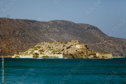 Cruise to the island of Spinalonga. Small boat on the blue lagoon. Spinalonga fortress on the island of Crete, Greece. Architecture on the island.