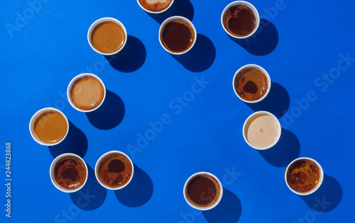 Paper cups with different types of coffee, cappuccino and macchiato on blue background