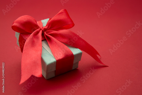 Close up gift box, birtday gift with red bow on red background. Free space for your text. Love, Valentine's Day, Mother's Day.