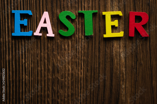 the word "Easter" is laid out on a wooden background in colored letters