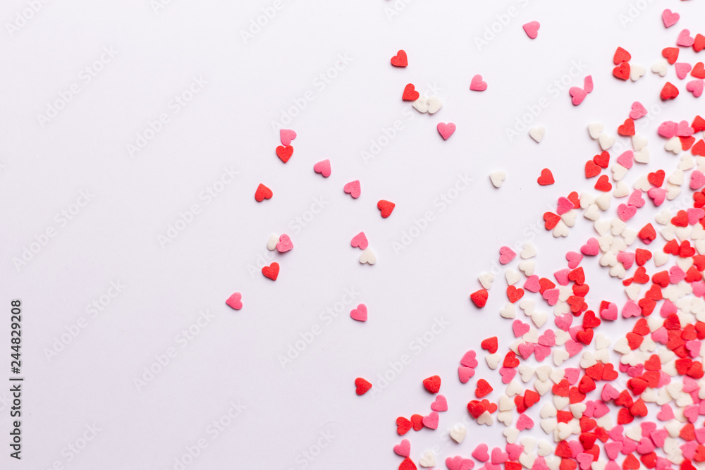 Red, pink and white heart shaped sweets scattered on white background. space for text. flat lay.