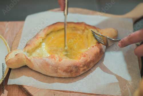 Georgian national food, Adzhar khachapuri and hands with fork photo