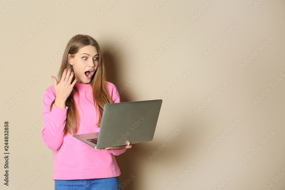 Emotional young woman with laptop celebrating victory on color background. Space for text Emotional young woman with laptop celebrating victory on color background. Space for text
