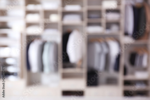 Blurred view of large wardrobe closet with clothes and home stuff