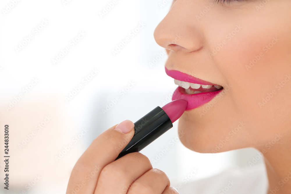 Obraz premium Beautiful woman applying lipstick on light background, closeup