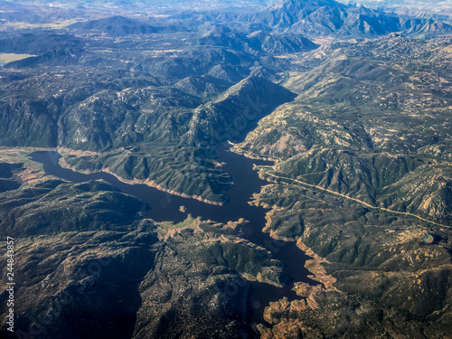 Fototapeta Naklejka Na Ścianę i Meble -  High Altitude Aerial Photo of Mountains, Hills and a River - with Rigid Peaks, Green Vegetation and Rocky Geography in the Western United States on a Bright, Hazy Day