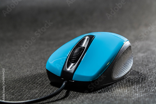 Computer mouse of bright blue color. Black details. Plastic. Modern technologies. Black background. Computer.