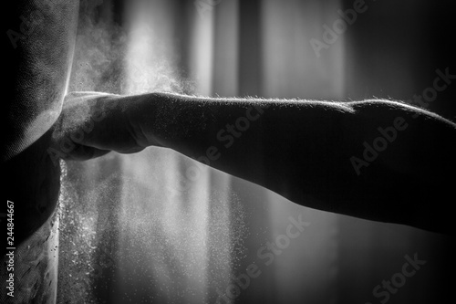 Shadowy, Black & White Close Up Action Photo of a Bare Knuckle Fist Hitting a Punching Bag with an Explosion of Dust