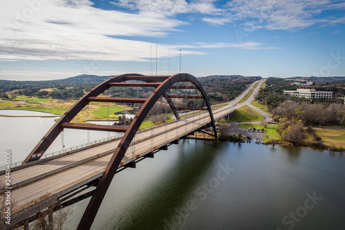 The 360 Pennybacker Bridge in Austin, Texas - with Empty Roads, a Still River and a Blue Sky with Clouds on a Bright and Sunny Day photo