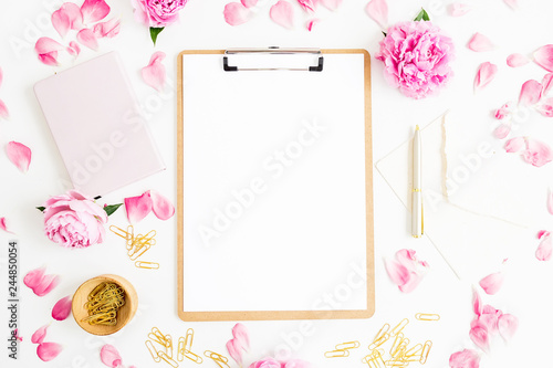 Work place with clipboard, pastel flowers and accessories on white background. Flat lay, top view. Freelancer concept