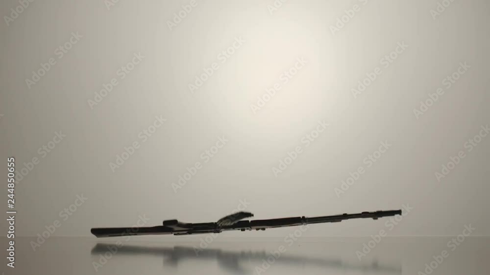 SLOW MOTION: Silhouette of AK Kalashnikov hitting about a white surface SLOW MOTION: Silhouette of AK Kalashnikov hitting about a white surface