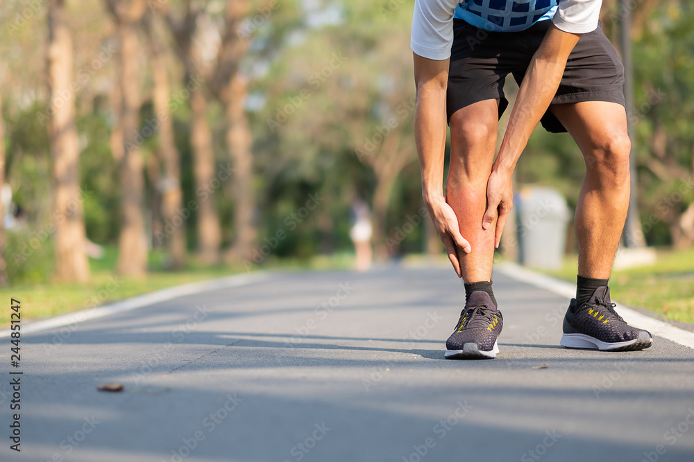 Young fitness man holding his sports leg injury. muscle painful during