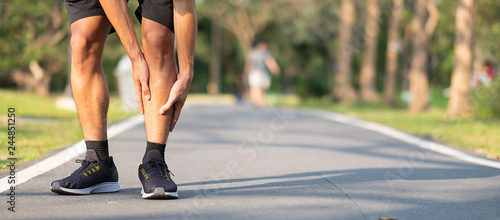 Young fitness man holding his sports leg injury. muscle painful during training. Asian runner having calf ache and problem after running and exercise outside morning. sport and healthy concepts