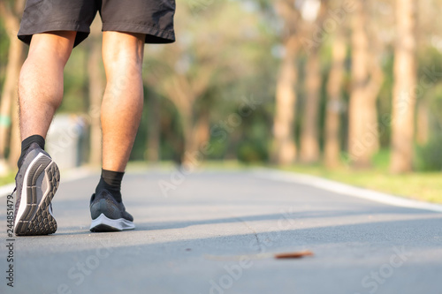 young fitness man legs walking in the park outdoor. male runner running on the road outside. Asian athlete jogging and exercise on footpath in sunlight morning. Sport healthy and wellness concepts