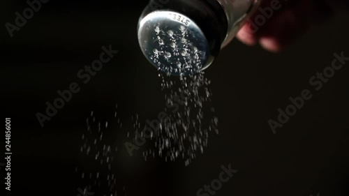 Salt falling in super slow motion from a salt shaker against black background  photo