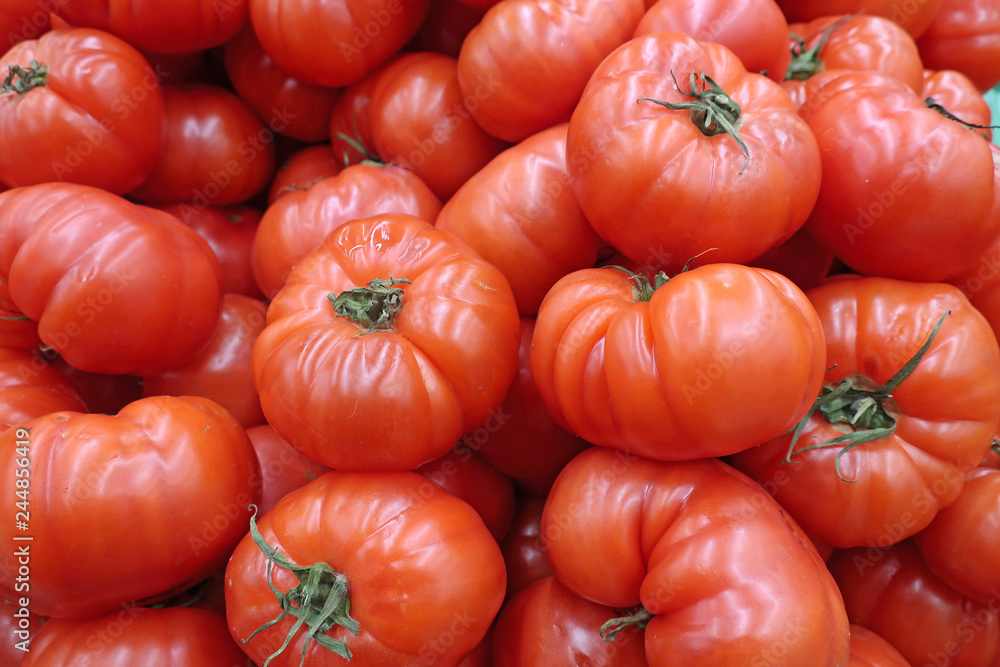 Many red large tomatoes on the counter in the market Many red large tomatoes on the counter in the market