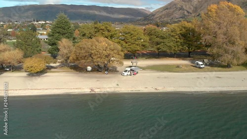 Slowmo Aerial Drone ascending from the beach overviewing the town and Lake Wanaka, New Zealand in autumn photo