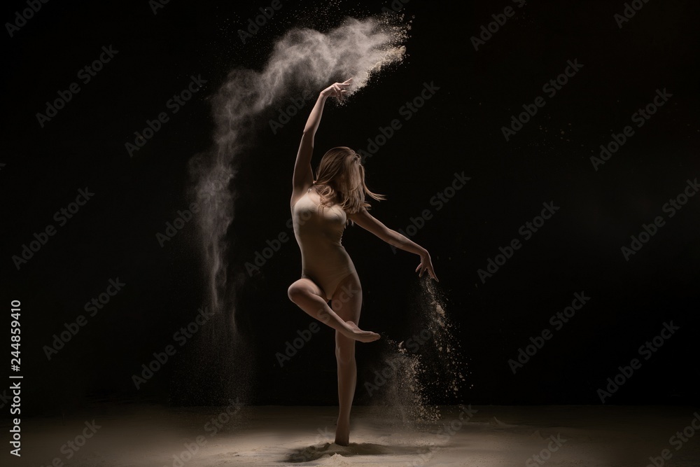 Sexy girl dancing gracefully in white dust cloud