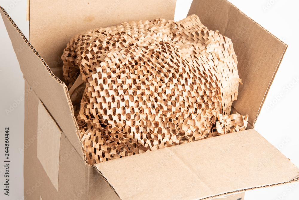 An open brown packaging box filled with recyclable brown filler paper.  Stock Photo | Adobe Stock