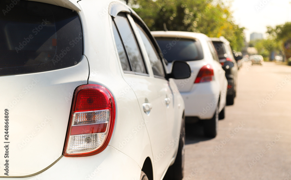 Closeup of back or rear side of white car parking in parking area beside the street in sunny day with natural background. 