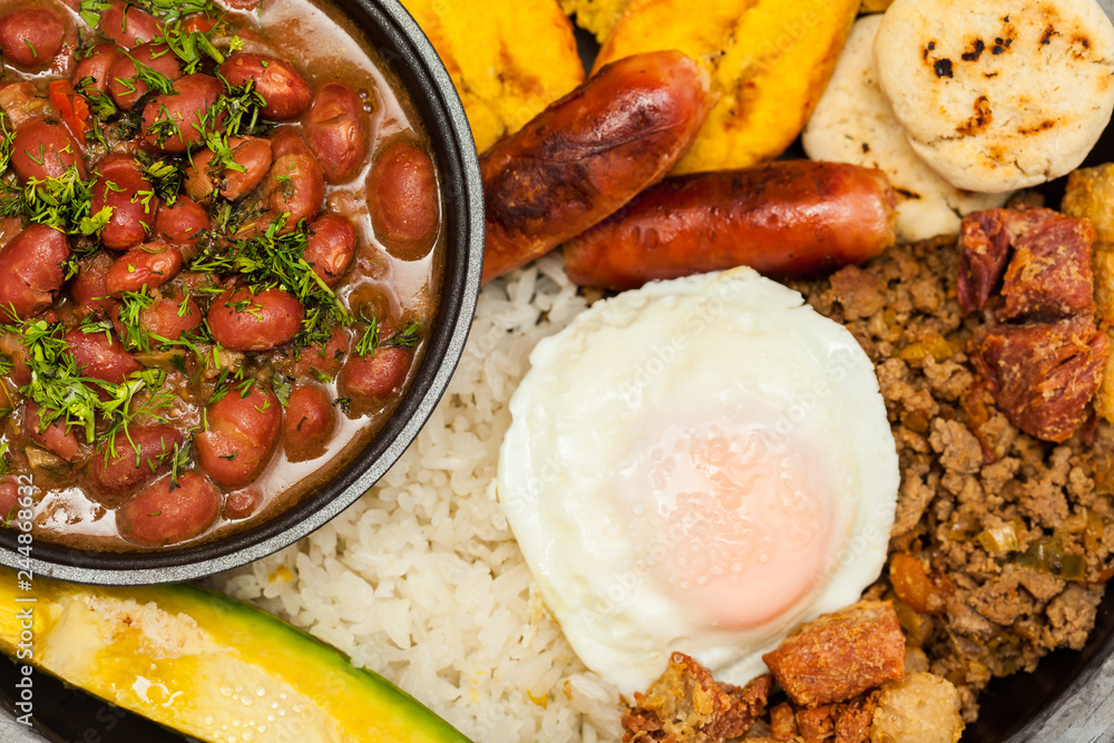 Traditional Colombian dish called Banda paisa: a plate typical of Medellin that includes meat, beans, egg and plantain - obrazy, fototapety, plakaty 