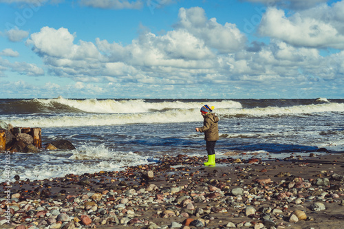 child in rubber boots on the shore of the cold Baltic Sea photo