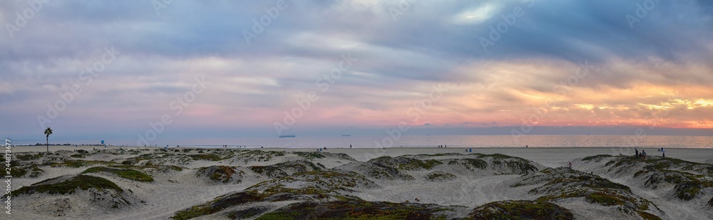 Obraz premium Coronado Beach in San Diego by the Historic Hotel del Coronado, at sunset with unique beach sand dunes, panorama view of the Pacific Ocean, silhouettes of people walking and boats in California, Unite