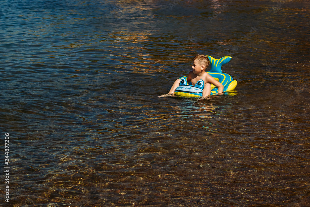 the boy floating on an inflatable baby boat the boy floating on an inflatable baby boat