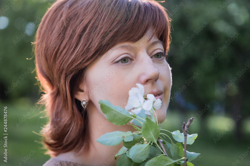 Girl with red hair in the park with blooming apple trees. Portrait of ordinary girl. Harmony concept Girl with red hair in the park with blooming apple trees. Portrait of ordinary girl. Harmony concept