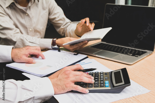 Group businessman hand using calculator Calculating bonus(Or other compensation) to employees to increase productivity.Writing paper on desk.