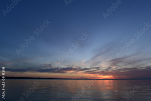 Obraz na płótnie Glowing sunlight in the clear blue twilight sky in the silence of the summer evening before nightfall on a lake w salonie