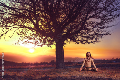 Yogi man meditating at sunset on the hills. Lifestyle relaxation emotional concept spirituality harmony with nature
