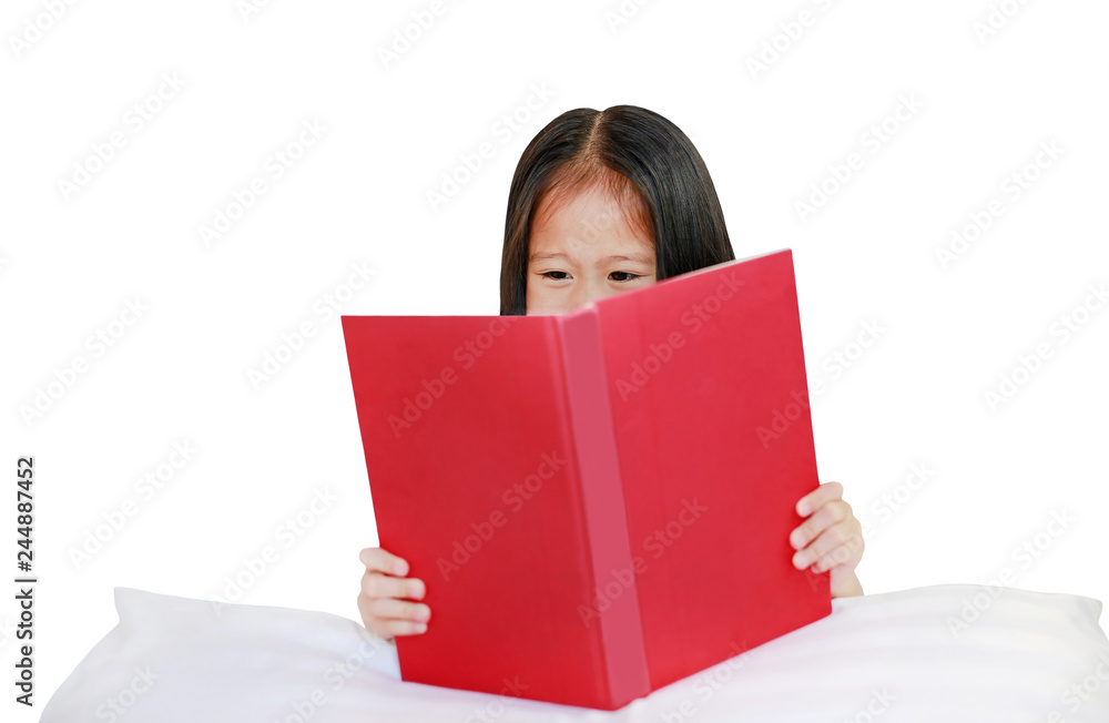 Beautiful little Asian child girl reading hardcover book lying with pillow on white background. Beautiful little Asian child girl reading hardcover book lying with pillow on white background.