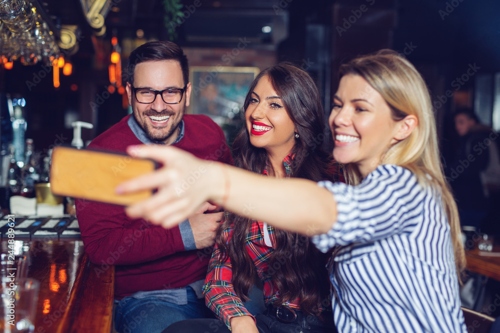 Fototapeta premium Three friends taking selfie in a bar. - Image