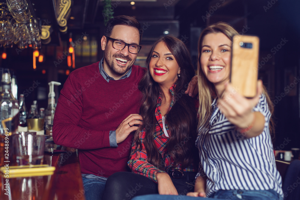 Three friends taking selfie in a bar. - Image