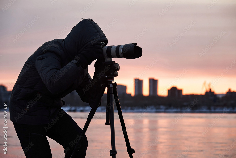 Photographer in the evening on the beach during a sunset with tripod 