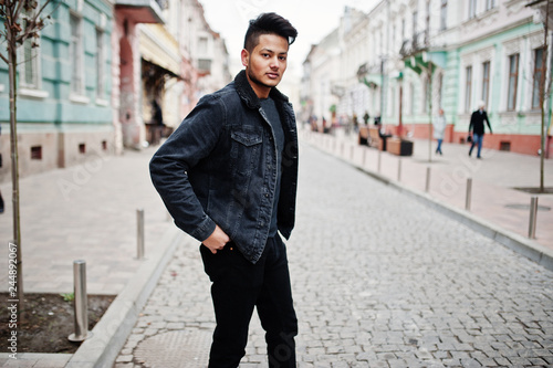 Handsome and fashionable indian man in black jeans jacket posed outdoor.