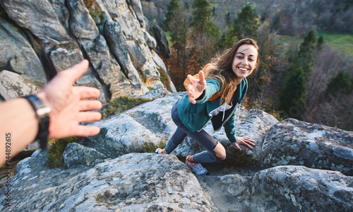 Fotografie first person view of a young pretty woman hiker climbed on the cliff, looking co
