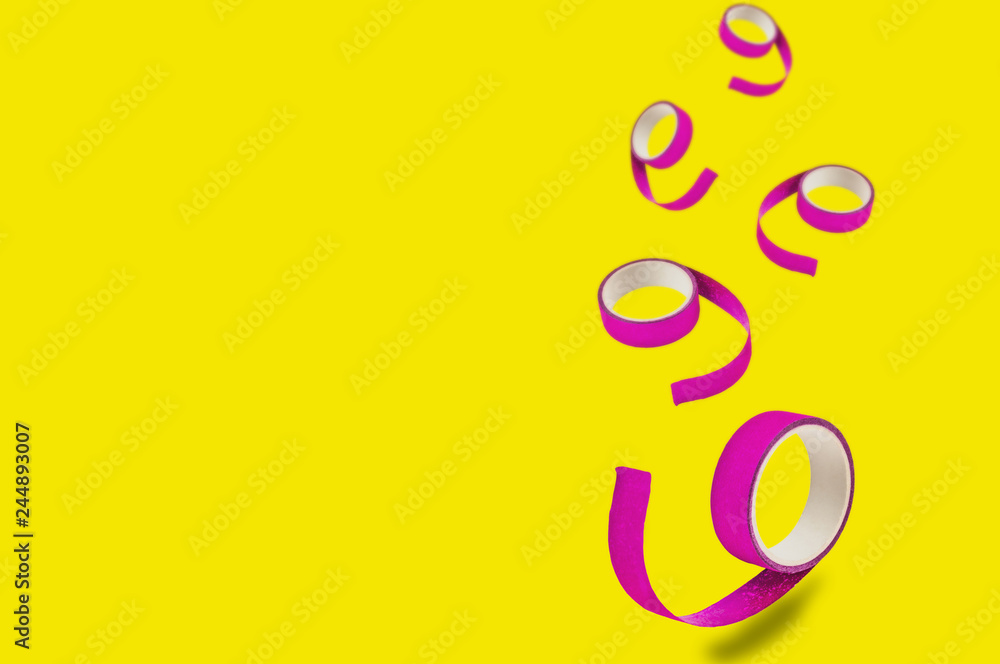 Fototapeta premium Falling rolls of violet sticky tapes on yellow background with copy space for your text