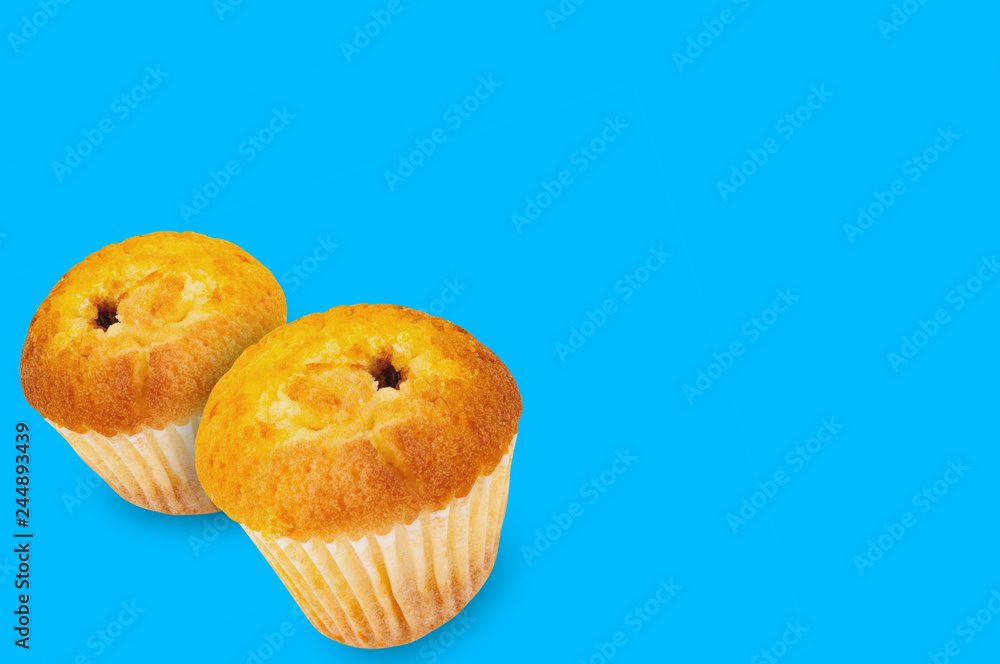 Pair of baked muffins without cream in paper form on blue background with copy space for your text Pair of baked muffins without cream in paper form on blue background with copy space for your text