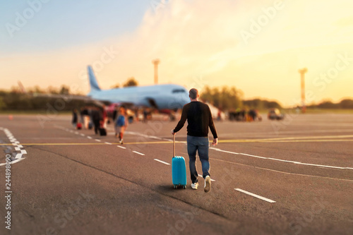 Konstfotografi Man tourist passager getting in to airplane at airport, walking from the terminal to the plane