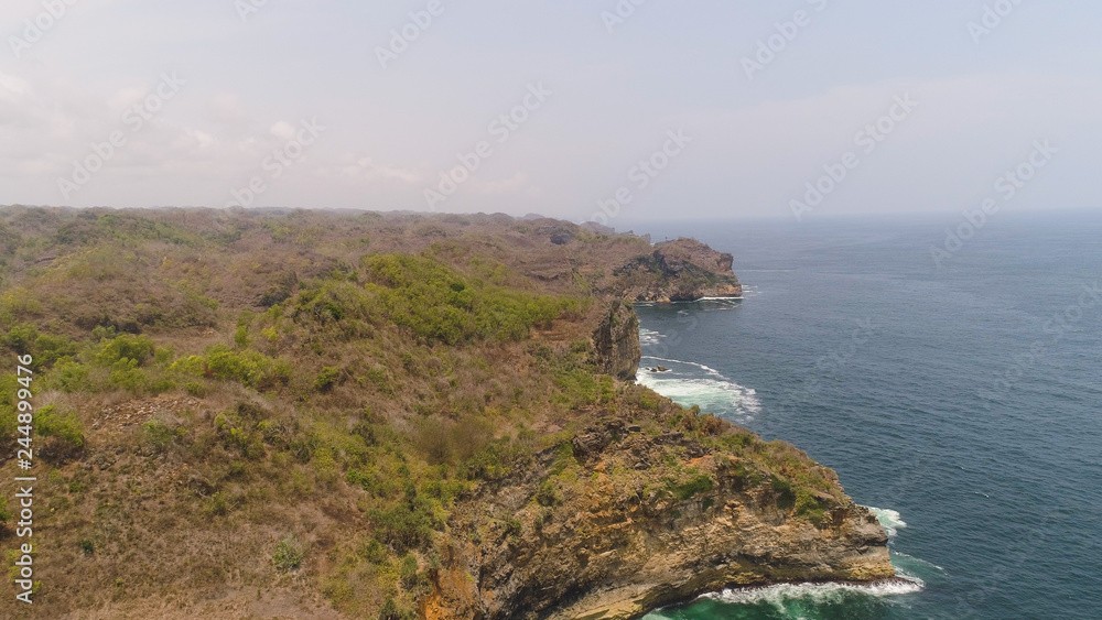 aerial view rocky coastline with cliffs, ocean surf with breaking waves in coast. seascape waves break on rocky shore java, indonesia aerial view rocky coastline with cliffs, ocean surf with breaking waves in coast. seascape waves break on rocky shore java, indonesia