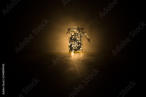 Christmas lights in a jar of glass on a wooden surface