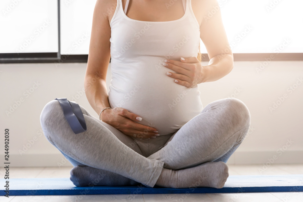 Happy smiling beautiful pregnant woman exercising at home - detail