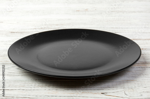 Perspective view. Empty dark matte dish for dinner on white wooden background