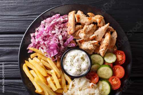Chicken shawarma with vegetables and sauce serving on a plate close-up. horizontal top view