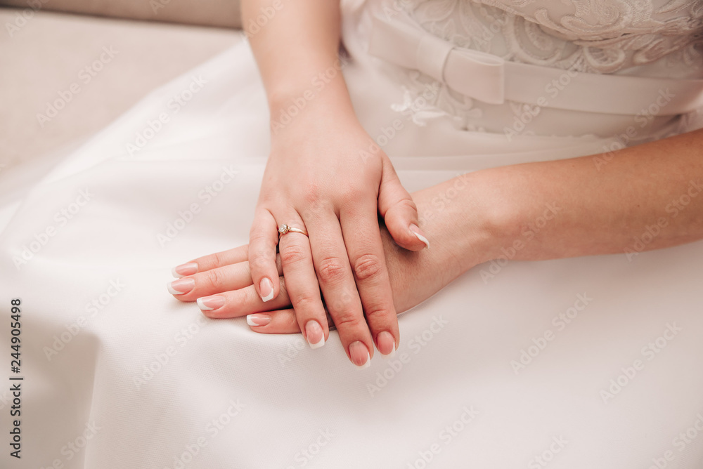 beautiful hands of a young girl with french manicure lie on a white dress