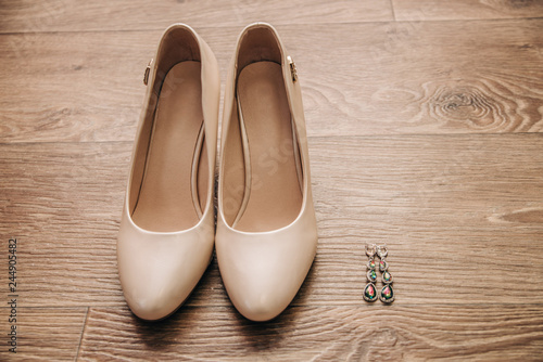 beige shoes and earrings on wooden background isolated attributes of the image of the bride